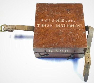 Timber box inscribed with: Patt 5 Heeling Error Instrument on lid and 0-486 on the side. Two leather straps with a buckle attached to two sides of the box.side