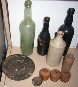 Relics recovered from the wreck of the Cambridgeshire; 3 glass bottles, 3 ceramic ink bottles, 2 ceramic bottles, 1 brass door knob, 1 engraved metal disc