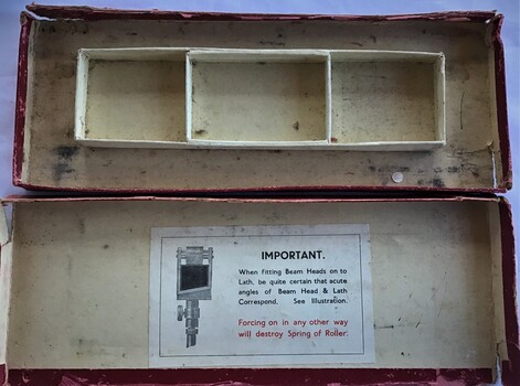 Rectangular cardboard box with separate compartments to hold beam compass and components. Outer colour is red with instructions on the inside. Box is badly damaged.a