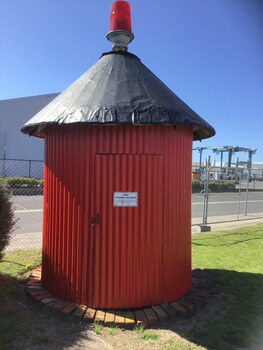 Red circular building with a red light on top of a black roof