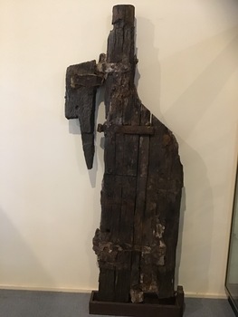 Remains of a timber rudder with 2 surviving gudgeons still bolted to it. Marks on the timber suggest the position of a a further 2 which have been lost to erosion. The top pintle survives and is still attached to timber which would have been originally attached to the ship's transom. The timber and metal of the pintle and gudgeon rudder are badly eroded and brittle.