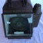Portable compass in metal case with glass front and spirit light compartment on left side.
