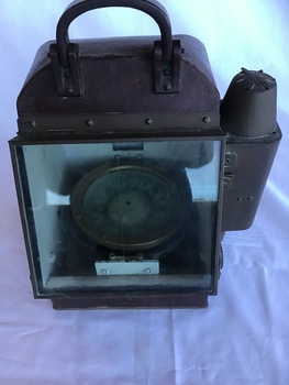 Portable compass in metal case with glass front and spirit light compartment on left side.