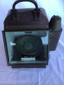 Portable compass in metal case with glass front and spirit light compartment on left side.