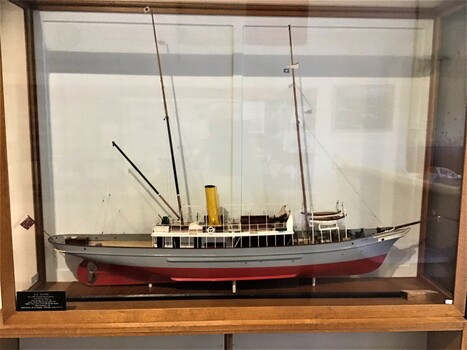 Model of the Pilot Vessel 'Alvina in a glass case. Model has red bottom, grey hull, white superstructure and yellow funnel. 
