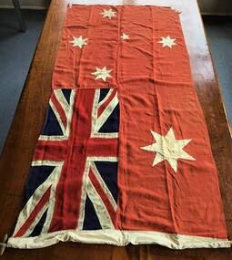 Australian Red Ensign flag, machine stitched and hand finished showing frayed edges and a portion of a halyard sisal rope and wooden toggle. 