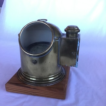 Top front side view of brass binnacle mounted on timber, with a view of the compass.
