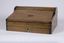 A mahogany lap writing desk with roll top lid shown in the closed position. A inlayed brass plaque on the top lid is inscribed with the letters M A.