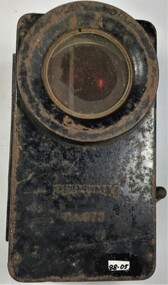 A small black rectangular metal box or flashlight which runs on batteries. It has a handle which  operates filters to produce either a red or green light.