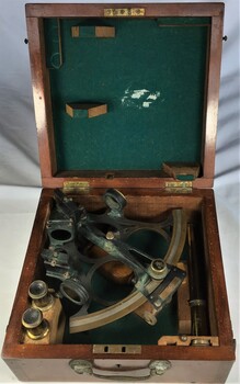 A sextant and accessories in wooden box with felt inlay.