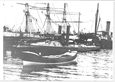 Black & white phot of HMVS Childers torpedo boat, with a moored lifeboat in the foreground and tri-masted square-rigged boat & steamship in the background .
