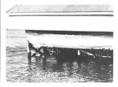 Black & white photograph of the oar/sail lifeboat Queenscliffe out of the water and under hard cover on piers at Queenscliffe