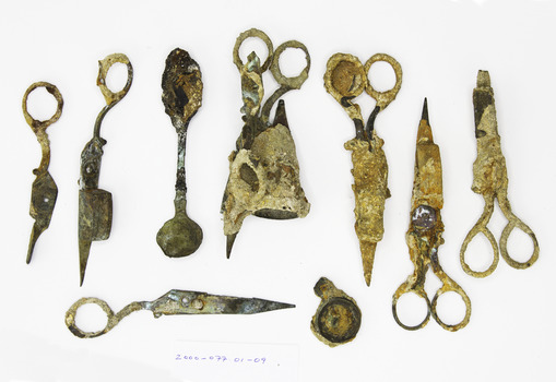 A collection of complete and remnant pieced of candle wick trimmers most heavily encrusted.