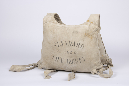 A canvas life jacket with two pouches, likely stuffed with kapok for buoyancy.