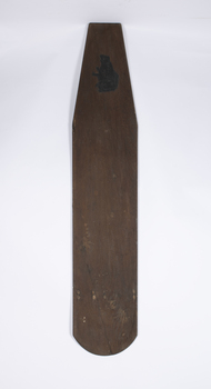  A plank or old ironing board hand modified to be used as a surfboard with a carved and painted frog emblem at the front end.