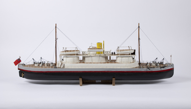 A  model of the HMVS Cerberus on a timber stand. Superstructure is white with a black hull to the waterline, then a red stripe and a grey freeboard. . 