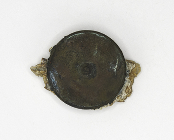 A round metal measuring tape, badly eroded and encrusted