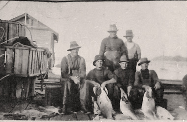 Black & white photo of fishermen with their catch of Yellowtail fish.