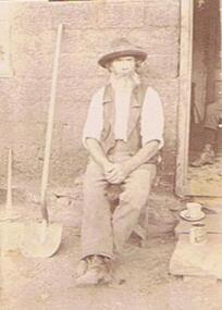 Photograph - COOK COLLECTION:  MAN SEATED ON STOOL OUTSIDE HOUSE