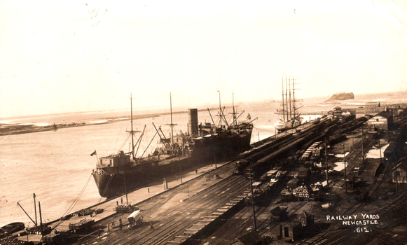 This black-and-white card shows ships berthed beside railway yards and wharves; on the card is printed “RAILWAY YARDS NEWCASTLE 612.”