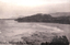 This black-and-white card shows a broad coastal beach backed by wooded hills; on the card is printed “Beach, Stanwell Park.”