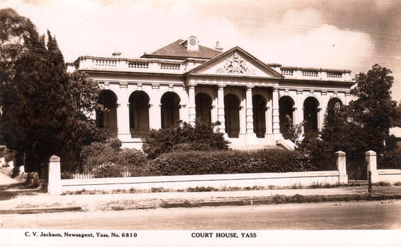 This black-and-white card shows a courthouse with an arched colonnade behind a garden and fence; on the card is printed “C. V. Jackson, Newsagent, Yass, No. 6810” and “COURT HOUSE, YASS”.