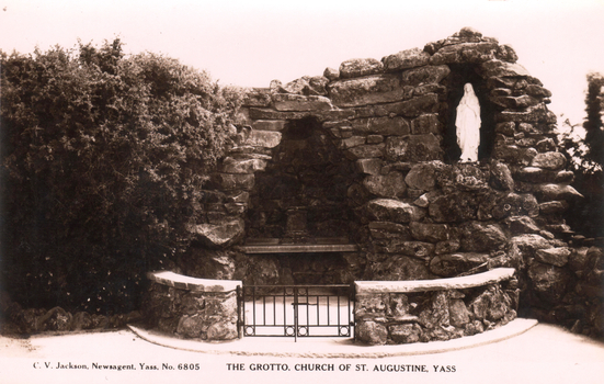 This black-and-white card shows a stone grotto containing a statue of the Virgin Mary; on the card is printed “C. V. Jackson, Newsagent, Yass, No. 6805” and “THE GROTTO, CHURCH OF ST. AUGUSTINE, YASS”.
