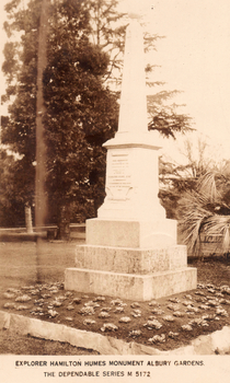 This black-and-white card shows an obelisk monument in a garden; on the card is printed “EXPLORER HAMILTON HUMES MONUMENT ALBURY GARDENS.” and “THE DEPENDABLE SERIES M 5172”.