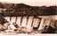 This black-and-white card shows water cascading over a weir in a rural valley; on the card is printed “C. V. Jackson, Newsagent, Yass, No. 6812” and “THE WEIR, YASS”.