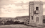 This black-and-white card shows a stone tower overlooking a coastal town; on the card is printed “MANLY FROM RED HILL.”