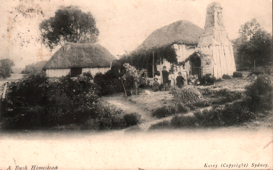 This black-and-white card shows a thatched bush homestead with people standing in the garden; on the card is printed “A Bush Homestead” and “Kerry (Copyright) Sydney.”