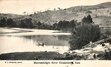This black-and-white card shows two people in a boat on a river beside a wooded hillside; on the card is printed “A. J. Shearsby, photo.” and “Murrumbidgee River Yeumburra Yass”.