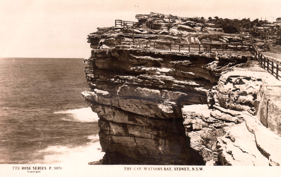 This black-and-white card shows a rocky coastal cliff with fenced walking paths; on the card is printed “THE ROSE SERIES P. 5976”, “Copyright.” and “THE GAP, WATSONS BAY, SYDNEY. N.S.W.”