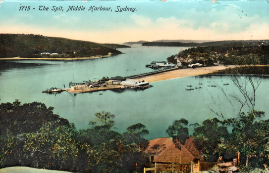 This coloured card shows an elevated view of a harbour, sand spit, wharves and small boats; on the card is printed “1715 - The Spit, Middle Harbour, Sydney.”