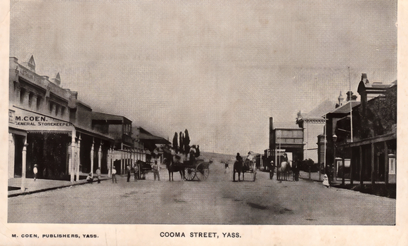This black-and-white card shows a broad commercial street with shops and horse-drawn vehicles; on the card is printed “M.COEN.”, “GENERAL STOREKEEPER.”, “M. COEN, PUBLISHERS, YASS.” and “COOMA STREET, YASS.”