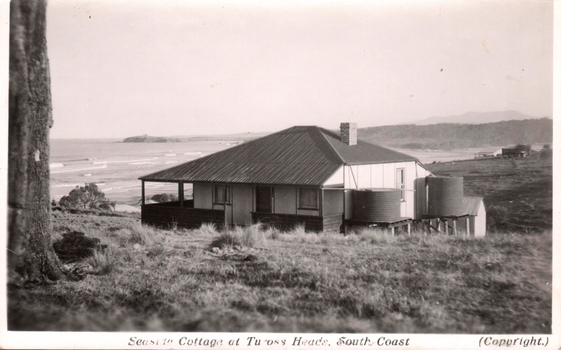 This black-and-white card shows a seaside cottage overlooking the coast; on the card is printed “Seaside Cottage at Tuross Heads, South Coast” and “(Copyright.)”.
