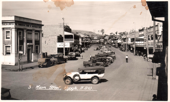 This black-and-white card shows a busy main street with parked motor vehicles and commercial buildings; on the card is printed “3. Main Street, Kyogle, N.S.W.”