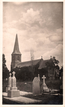 This black-and-white card shows a church with a tall steeple behind a cemetery: There is no visible printed caption.