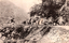 This black-and-white card shows a road cutting through a rocky gorge with people and a horse-drawn cart: On the card is printed “PART OF THE CUTTING, BARREN JACK. WILL THOMSON, PUBLISHER. C. N. HOWARD, YASS. COPYRIGHT PHOTO.”