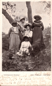 This black-and-white card shows five women and girls posed outdoors among trees: On the card is printed ““AUSTRALIAN PEARLS.” [Star Photo. Co., Copyright.]” The handwriting appears to read: “Thanks very much for Post Card. Still hot & no rain. Would like to be able to sit at a nice place. Much love from Aunty B.”