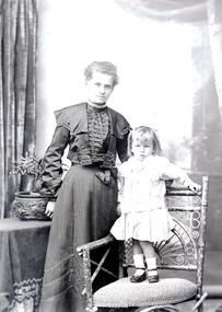 Photo of a woman and a child standing on a chair.