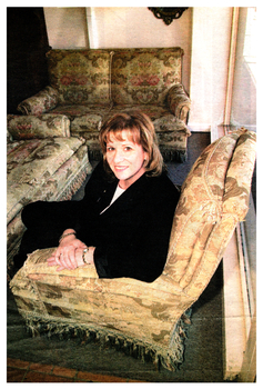 Colour photo of Lorainne Isaacs of Valentines, Furniture and Auctions, enjoying the luxurious set of the lounge chairs and sofa.