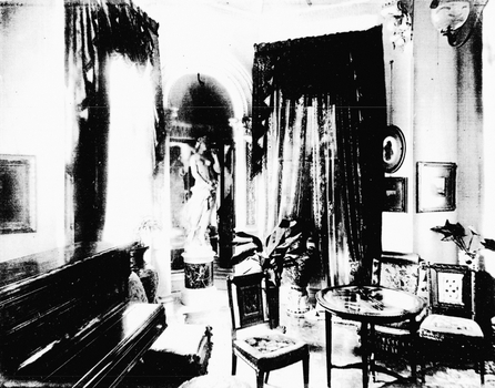 Black and White photo of a music room with piano, chairs and a coffee table