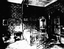 Black and White photo of a bedroom with sofa, chair and iron framed bed