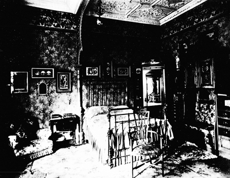 Black and White photo of a bedroom with sofa, chair and iron framed bed