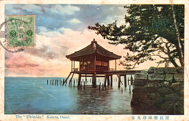 This coloured card shows a traditional pavilion standing over water beside pine trees and a stone wall: On the card is printed “The “Ukimido” Katata, Oumi. 近江堅田浮見堂”. The Japanese 近江堅田浮見堂 translates as “Ukimidō (Floating Hall), Katata, Ōmi.”