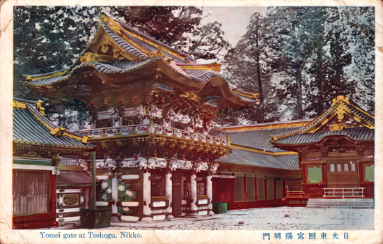 This coloured card shows an ornate Japanese shrine gate and surrounding buildings in a snowy setting: On the card is printed “Yomei gate at Toshogu, Nikko. The Japanese translation is “Yōmeimon Gate at Nikkō Tōshōgū Shrine.”