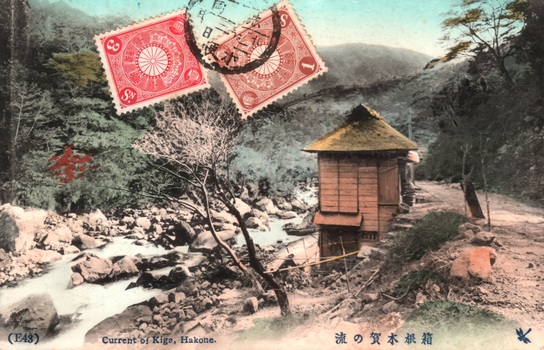 This coloured card shows a rocky stream flowing beside a small wooden building in a wooded valley: On the card is printed “(E43) Current of Kiga, Hakone. The Japanese itranslates as “The stream at Kiga, Hakone.”