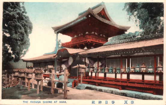This coloured card shows traditional Japanese shrine buildings with a tower and rows of lanterns: On the card is printed “THE KASUGA SHRINE AT NARA The Japanese translates as “Kasuga Shrine, Nara.”