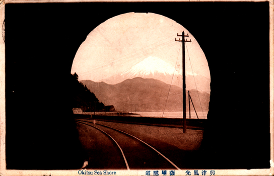 11731.035 This coloured card shows railway tracks beside the shoreline with Mount Fuji in the distance: On the card is printed “Okitsu Sea Shore. The Japanese translates as “Scenery of Okitsu — the tunnel at Satta Pass.”